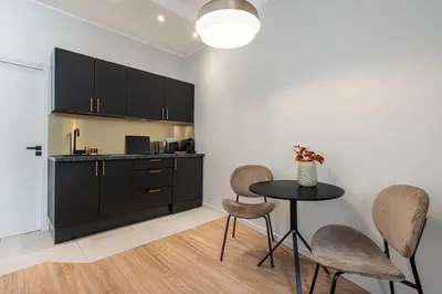 a kitchen with black cabinets and a table and chairs at Coeur de La Libé - Ideal couple & FRIENDS - CENTRAL & COSY - TRAM & Supermarkets -AC -Bed XXL in Nice