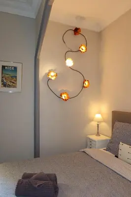 a bedroom with a bed with lights on the wall at Charming studio overlooking a beautiful garden in Nice