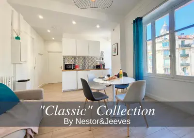 a living room with a table and chairs and a kitchen at Nestor&Jeeves - BLEU BUFFA - Central location in Nice