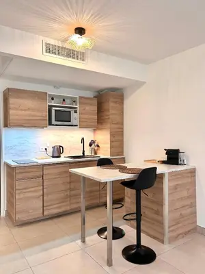a kitchen with wooden cabinets and a table and chairs at Appartement neuf coup de coeur entre Èze et Monaco in Èze