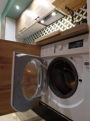 a washing machine in a kitchen next to a microwave at Cosy Haven 5 min from Nice Carnival Hyper-Center! in Nice