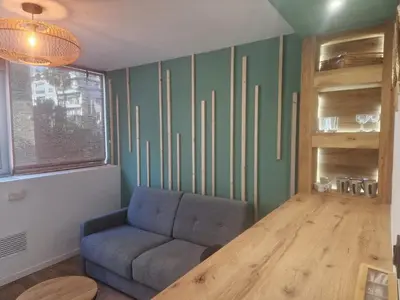 a living room with a couch and a wooden table at Cosy Haven 5 min from Nice Carnival Hyper-Center! in Nice