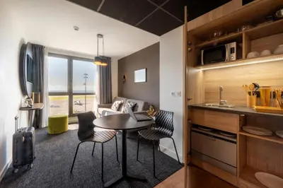 a kitchen and a living room with a table and chairs at Nemea Appart Hotel Nice Arenas Aéroport in Nice