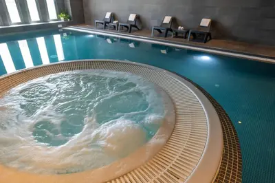 a hot tub in a swimming pool with chairs at Nemea Appart Hotel Nice Arenas Aéroport in Nice