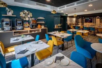 a dining room with tables and blue chairs at Nemea Appart Hotel Nice Arenas Aéroport in Nice