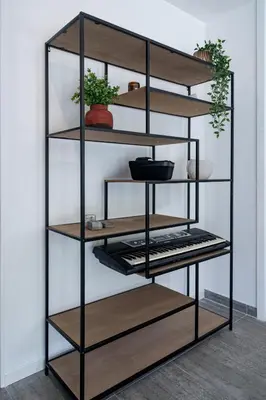 a black shelving unit with wooden shelves and potted plants at Le calme à Nissa la Bella in Nice