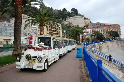 a white bus is parked next to a blue fence at Downtown in Nice