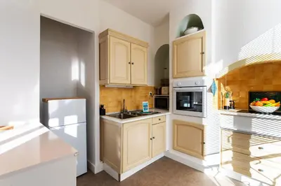 a kitchen with wooden cabinets and a white refrigerator at LE PROVENCE AP4389 By Riviera Holiday Homes in Villefranche-sur-Mer