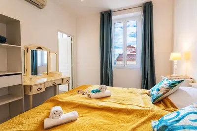 a bedroom with towels on a bed with a window at LE PROVENCE AP4389 By Riviera Holiday Homes in Villefranche-sur-Mer