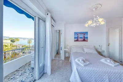 a white bedroom with a bed and a balcony at FAMILY APARTMENT SEA VIEW in Nice