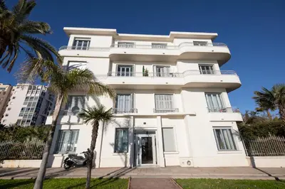a white building with palm trees in front of it at FAMILY APARTMENT SEA VIEW in Nice