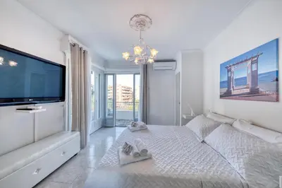 a white bedroom with a large tv and a bed at FAMILY APARTMENT SEA VIEW in Nice