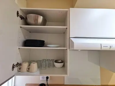a kitchen with white cabinets and utensils at Studio cosy - Proche mer et gare in Nice