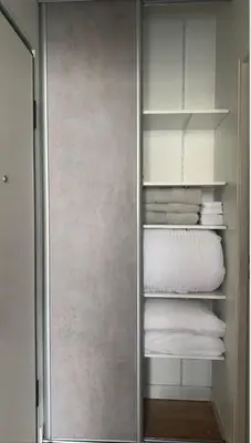 a walk in closet with white shelves and towels at Studio meublé in Nice