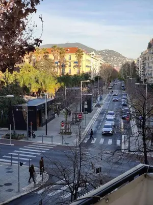 a city street with cars and people crossing the street at Studio meublé in Nice
