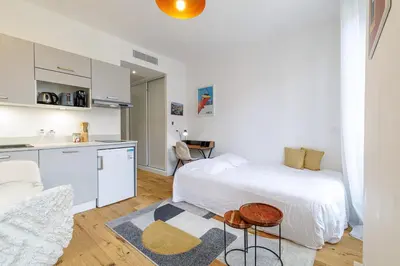 a white bedroom with a bed and a kitchen at Charming City Center Studio 406 in Nice