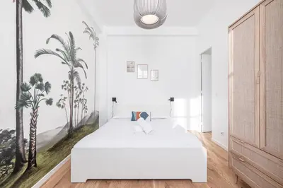 a bedroom with a white bed with palm trees on the wall at Lovely 2 Bdr Nice Harbor in Nice