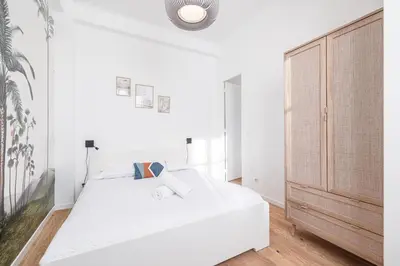 a white bedroom with a bed and a wooden door at Lovely 2 Bdr Nice Harbor in Nice