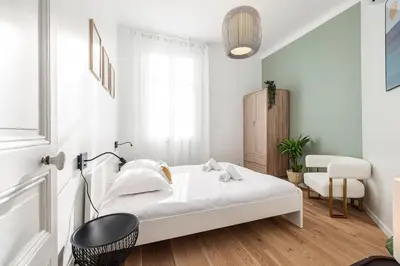 a white bedroom with a bed and a chair at Lovely 2 Bdr Nice Harbor in Nice