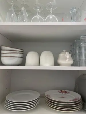 a white shelf with plates and bowls and glasses at 2 pièces dans le Vieux Nice - à 3 min de la mer et du célèbre cours Saleya in Nice