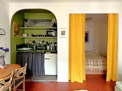 a kitchen with yellow curtains in a room with a bed at Casa Marguerite, studio atypique in Nice