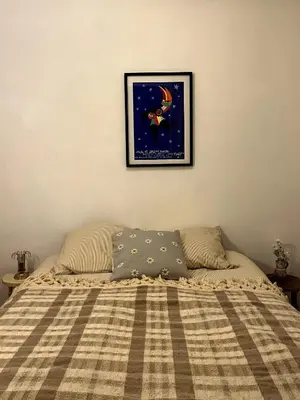 a bed with a blanket and a picture on the wall at Casa Marguerite, studio atypique in Nice