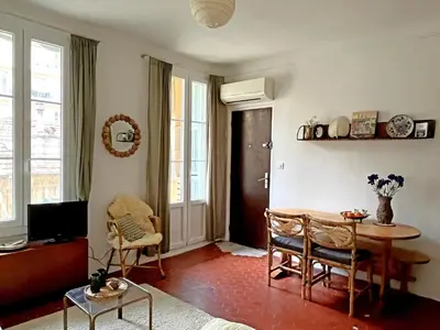 a living room with a table and chairs and a tv at Casa Marguerite, studio atypique in Nice