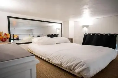 a bedroom with a large white bed and a mirror at Appartement avec mezzanine in Nice