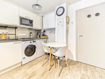 a kitchen with white cabinets and a table and chairs at Magnifique T2 neuf - résidence neuf- Hyper central in Nice