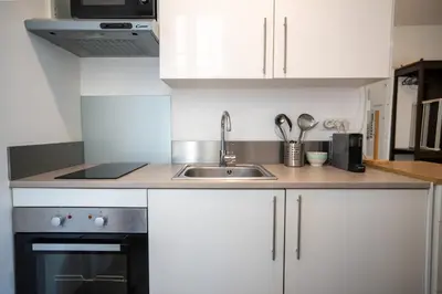 a kitchen with white cabinets and a sink and a stove at GuestReady - A peaceful stay near the marina in Nice