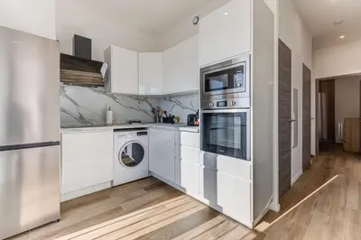 a kitchen with white cabinets and a washer and dryer at Les Grands Cèdres - Wifi, AC, Parking in Nice
