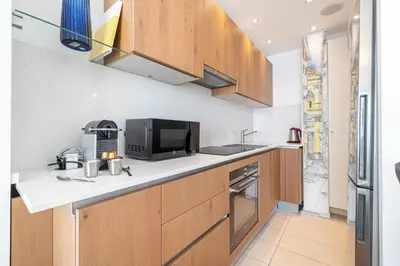 a kitchen with wooden cabinets and a microwave at MY CASA - ETAT UNIS 93 INDIGO - Amazing Sea View Aprt with AC in Nice