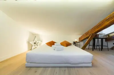 a bedroom with a white bed and a piano at MY CASA - MASSENA 44 - Stunning studio on Masséna Square in Nice
