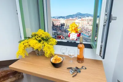 a window sill with a table with glasses and flowers at MY CASA - MASSENA 44 - Stunning studio on Masséna Square in Nice