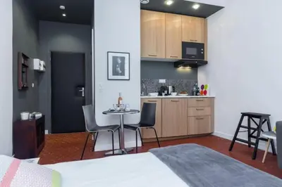 a room with a bed and a table and a kitchen at MY CASA - DROITE - Bright studio in the Old Town in Nice