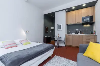 a bedroom with a large bed and a kitchen at MY CASA - DROITE - Bright studio in the Old Town in Nice