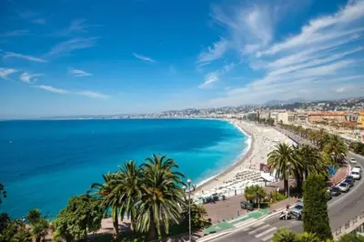 a view of a beach with palm trees and the ocean at MY CASA - DELOYE - Spacious Quiet studio w AC near Old Town in Nice