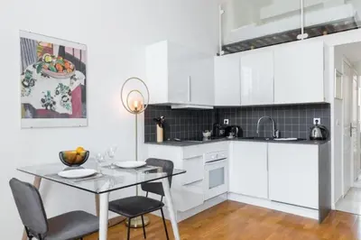 a kitchen with white cabinets and a table and chairs at MY CASA - DELOYE - Spacious Quiet studio w AC near Old Town in Nice