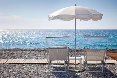 two chairs under an umbrella on the beach at MY CASA - DELOYE - Spacious Quiet studio w AC near Old Town in Nice