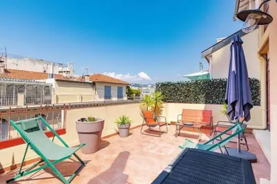 a patio with chairs and an umbrella on a balcony at MY CASA - LAMARTINE - Studio w terrace and AC Very central in Nice
