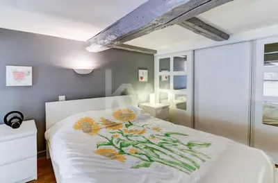 a bedroom with a white bed with flowers on it at Spacieux Duplex - Zone Piétonne in Nice