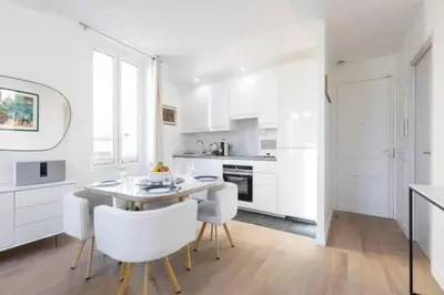 a kitchen with white cabinets and a table and chairs at MY CASA - MOULIN - Stunning 1 bedroom Apt on the Port in Nice