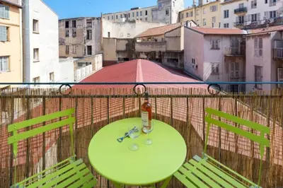 a green table on a balcony with a bottle and scissors at MASSENA 33 - Cosy Studio City Center in Nice