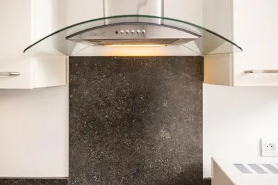 a kitchen with a hood over a black counter at Appartement rénové - Terrasse - Parking - BM in Nice