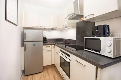 a kitchen with white cabinets and a microwave at Appartement rénové - Terrasse - Parking - BM in Nice