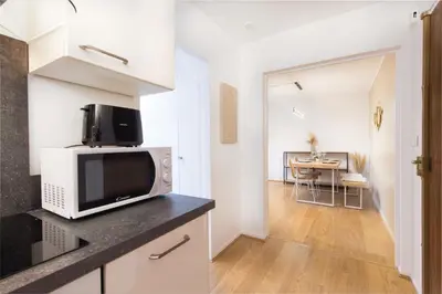a kitchen with a microwave and a living room at Appartement rénové - Terrasse - Parking - BM in Nice