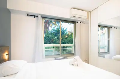 a bedroom with a white bed and a window at Appartement rénové - Terrasse - Parking - BM in Nice