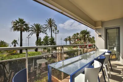a balcony with a blue table and chairs and palm trees at Sublime Appartement Promenade des Anglais (1) in Nice