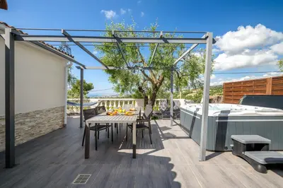 a deck with a table and chairs and a hot tub at Villa vue mer, terrasse et spa in Nice