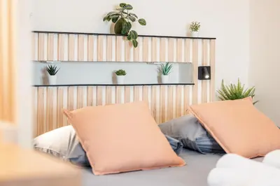 two pillows on a bed with plants on the wall at FEEL HOME - COLLET in Nice
